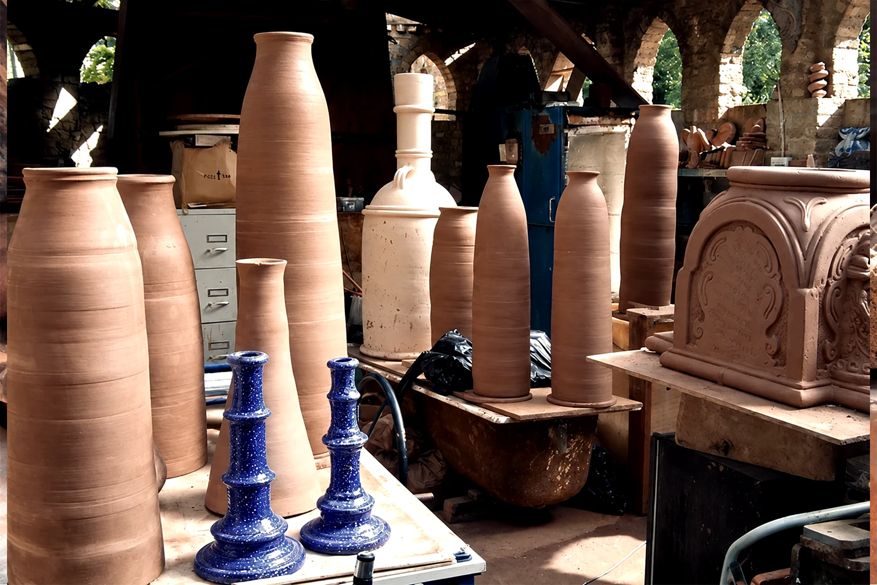 Tall terracotta vessels, blue glazed ceramics and ornamental forms in the owner’s workshop