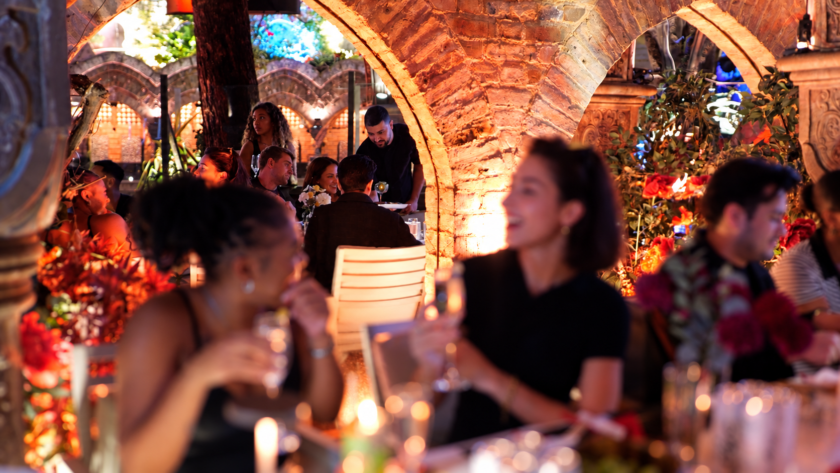 Guests enjoying an evening beneath the warmly lit stone arches of The Shisha Garden