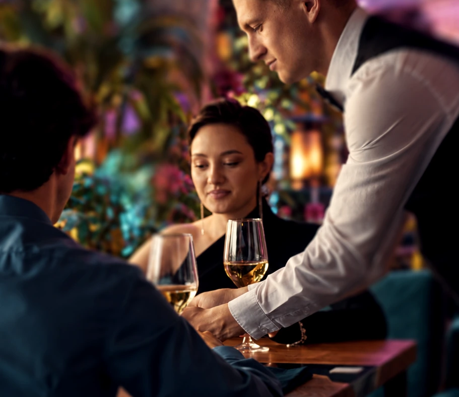A couple being served wine at an intimate table in the Garden