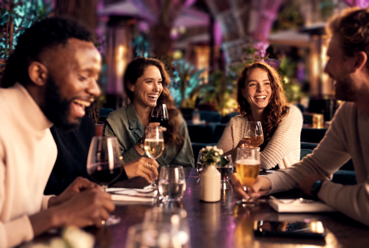 Friends sharing dinner and conversation in the warmly lit Garden