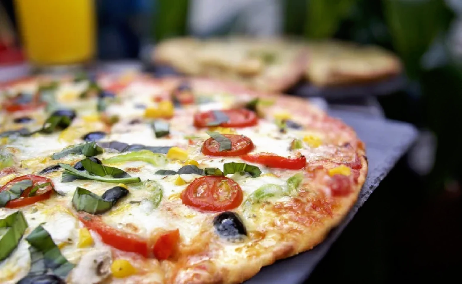 A freshly baked pizza topped with vegetables and olives