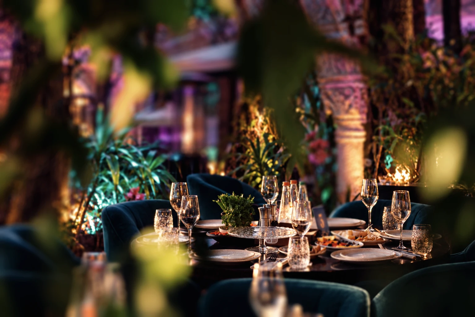 Tables beneath stone arches, hanging greenery and warm garden lighting