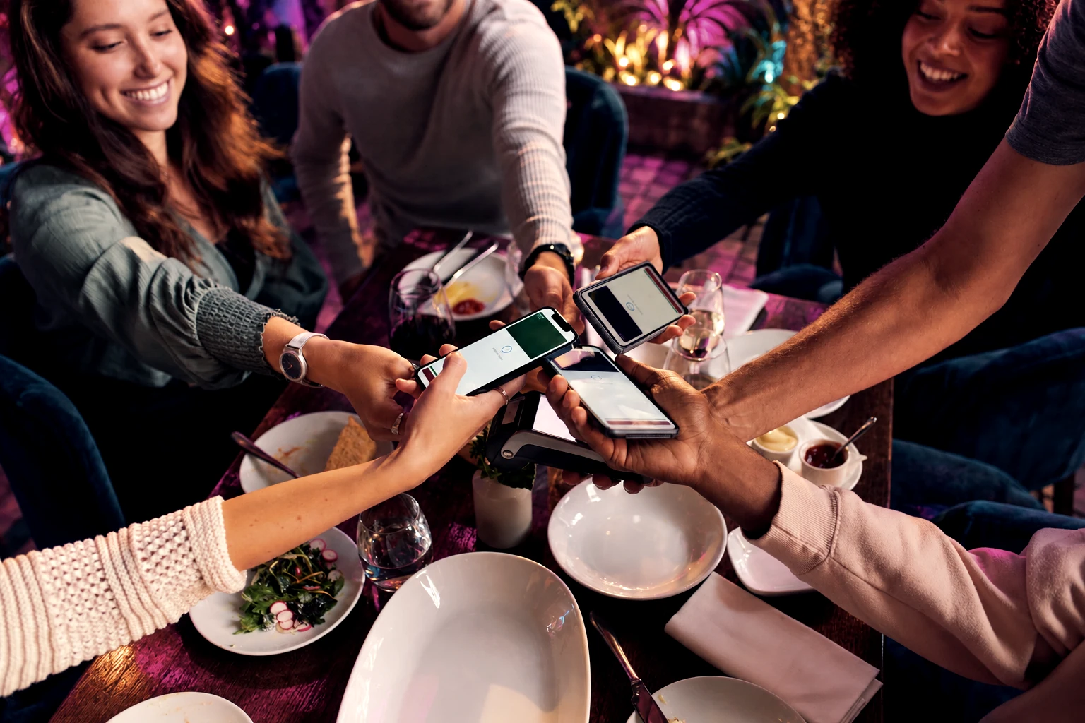 Friends using their phones around a shared restaurant table